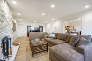 basement recreation room with large sectional sofa white painted brick fireplace