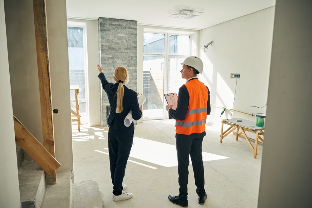 Businesswoman and foreman standing in room which needs redecoration
