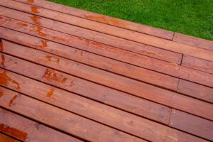 Timber deck after rain, wet timber decking. Top view of wet wooden deck. Water on a freshly sealed wood deck after a rainstorm backyard, daytime